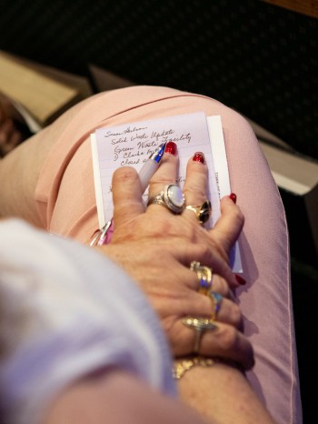 Photograph of a woman's hands taking notes about rebuilding at the city council meeting