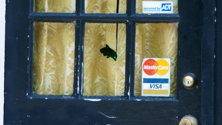 A merchant's closed door, displaying the Visa and Mastercard logos.