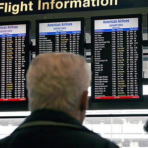 man looks at flight info on airport monitor