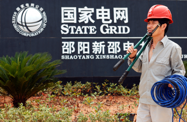 photograph of A electrician stands in front of a State Grid branch in China's Hunan province in 2011.an