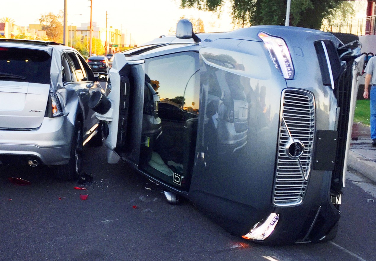 An image showing the aftermath of a self-driving car accident, with an uber vehicle on its side