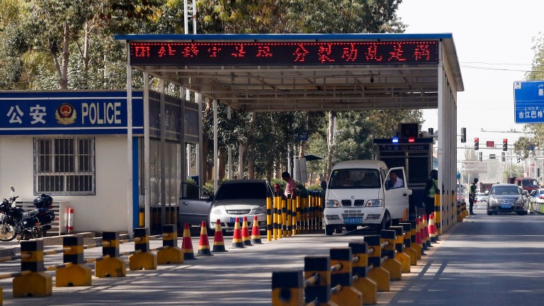 Uighur drivers have their vehicles checked at a police check point in Hotan