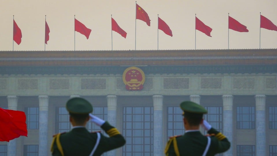 Chinese paramilitary armed policemen salute as red flags flutter in front of the Great Hall of the People in Beijing.