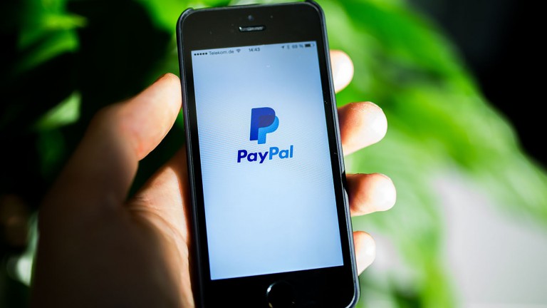 Someone's hand holding a phone with the PayPal app loaded.