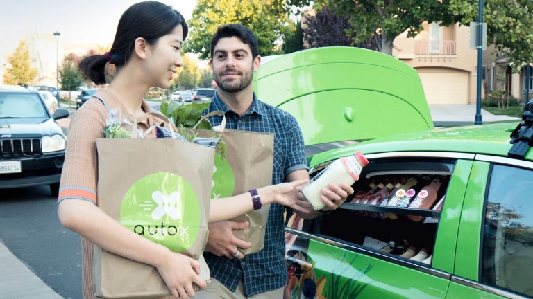 People select healthy snacks from the backseat of a self-driving car developed by the startup AutoX.