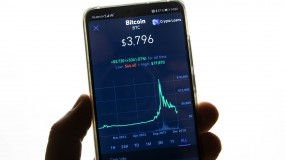 A mobile phone showing the price of Bitcoin and a graph of its fluctuation over time.