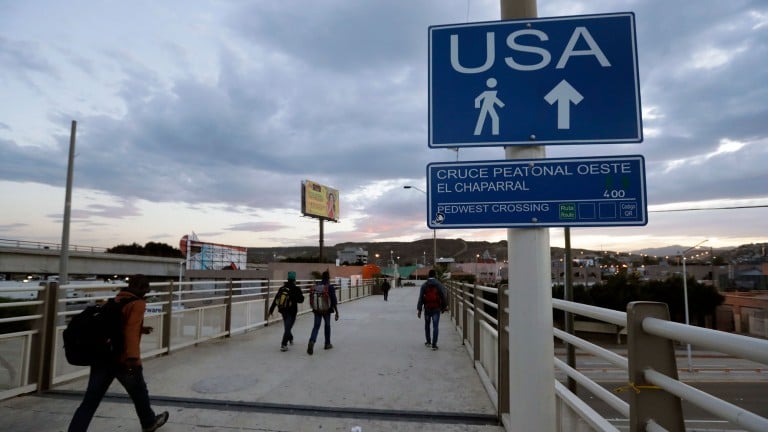 People walk towards the US border crossing in Mexico