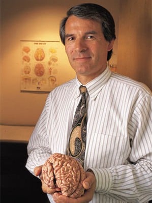 An image of a man holding a model of a human brain