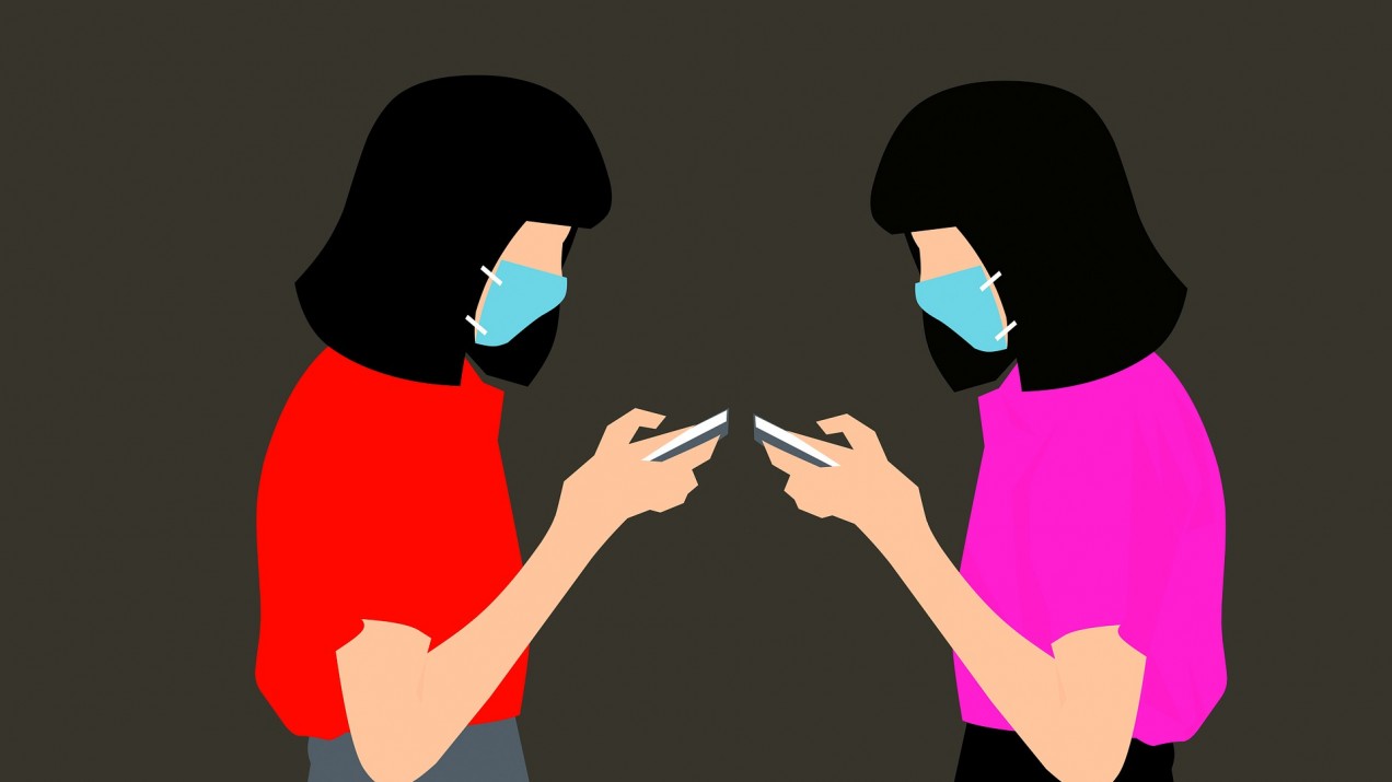 Women wearing face masks checking their phones