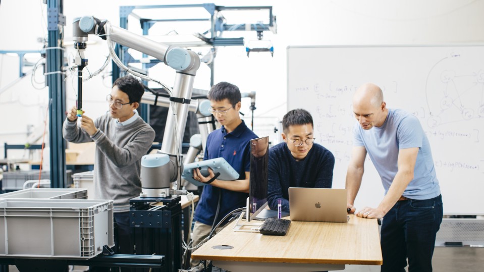 Covariant co-founders work on their robotic arm.