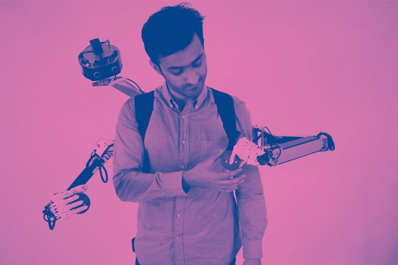Image of man exchanging a ball with a hand of the robotic-armed backpack.