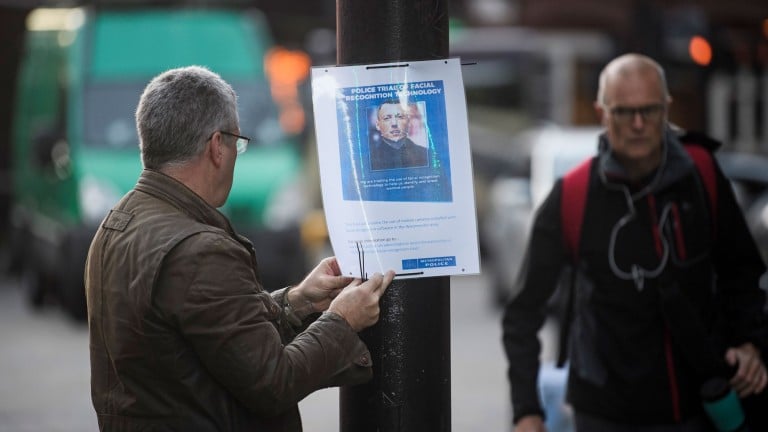 A man puts up a poster describing London's Metropolitan Police's face recognition system trial