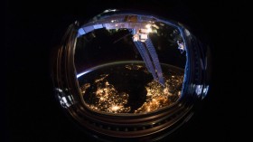 An astronaut helmet reflecting a light-filled earth