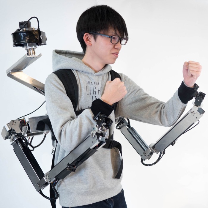 Image of man in a boxing stance wearing robotic-armed backpack.