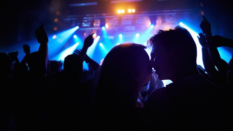 An image of people stealing a kiss in a crowd.