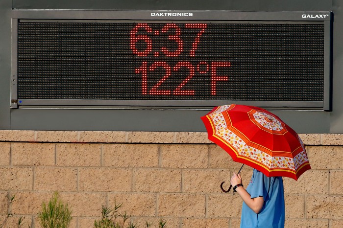 Photo of person holding an umbrella in front of a screen showing the time 