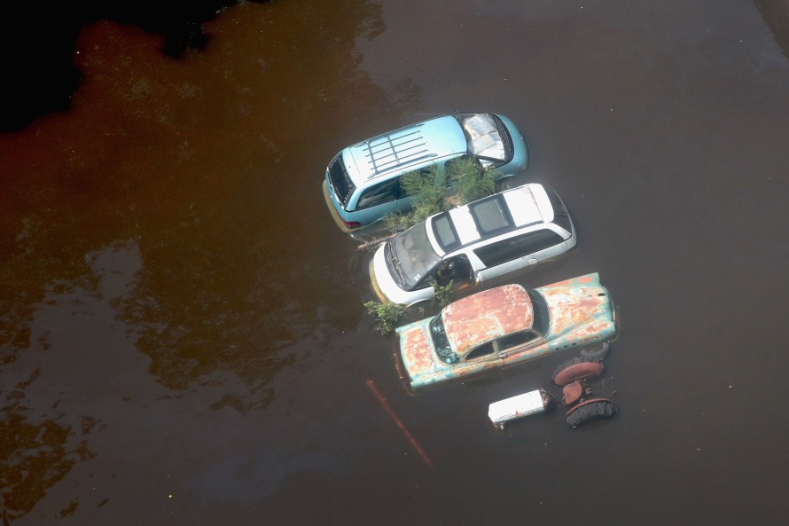 Photo of three cars and a tractor in flood waters