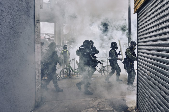 Riot Police begin shooting tear gas and  wielding their batons at protestors during a skirmish in Yuen Long.  The protestors are protesting the suspected collusion with Triads from last weeks Yuen Long West Rail station attacks on protestors and civilians.  Yuen Long, New Territories, Hong Kong. July 27th, 2019.