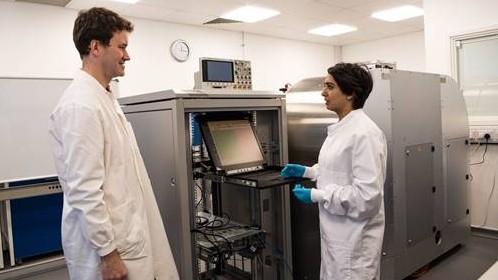 Photo of two researchers standing in front of prototype of DNA data storage machine