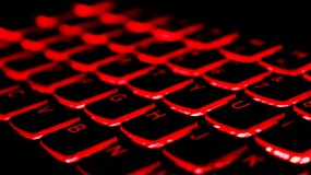An image of a computer keyboard in the dark, with a red back light.