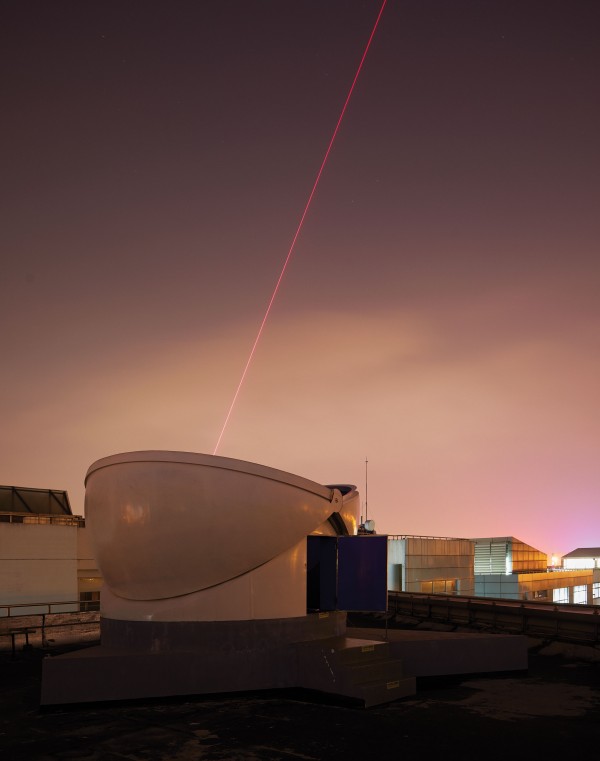 Photograph of receiver at night with a spotting laser visible in the evening sky.