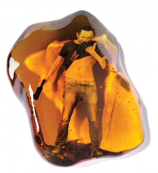 conceptual illustration of a young man drinking a beer, trapped inside a piece of amber