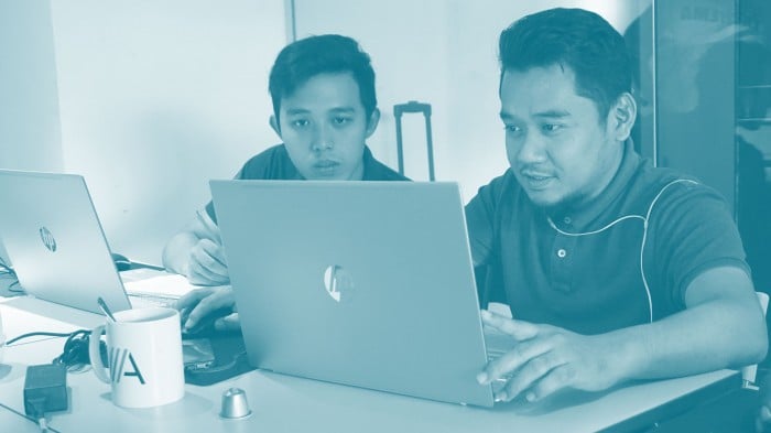 Two remote employees in Kuala Lumpur work on laptops