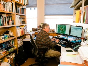 Photograph of Chuck as he works in his office at the Missoula Fire Lab and uses a program that models fire activity and the probability of spread. The program allows scientists to model fire spread and subsequently determine if action needs to be taken or what action they should be thinking about. Or, conversely, no action at all.