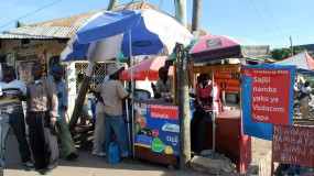 A street vendor in Tanzania with signs showing that they accept Vodafone's M-Pesa digital payment system.