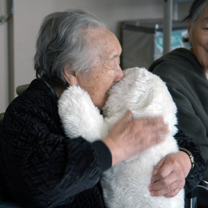 senior citizen hugs fluffy puppy. majorlt adorable.