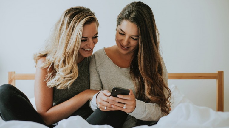 image of teen girls on bed looking at phone sexting sextortion selfie