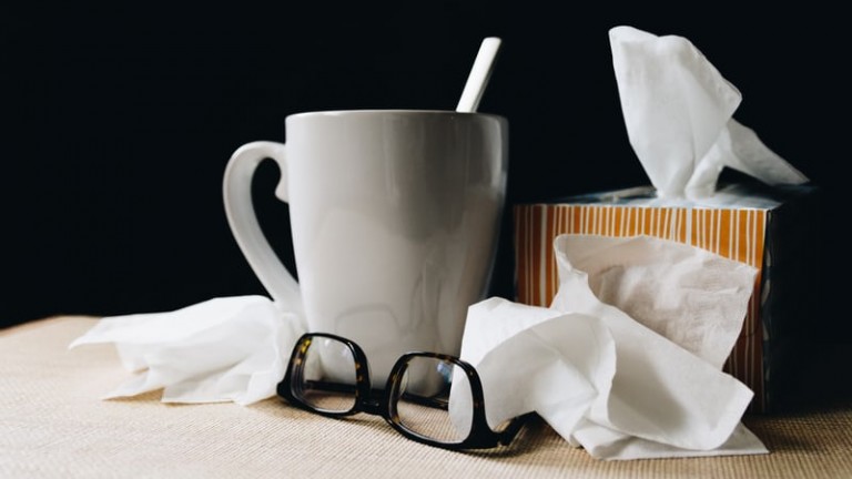 coronavirus vs flu image of coffee mug tissues bedside table influenza