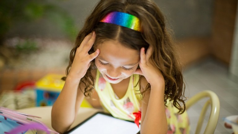 girl with rainbow headband reading tablet kindle