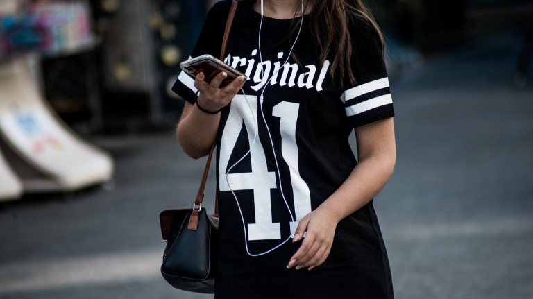 woman walking with iphone smartphone cell phone distracted texting app on street