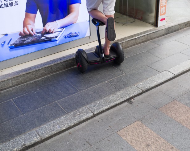 Photo of a man on a motorized scooter looking at a hardware advertisement