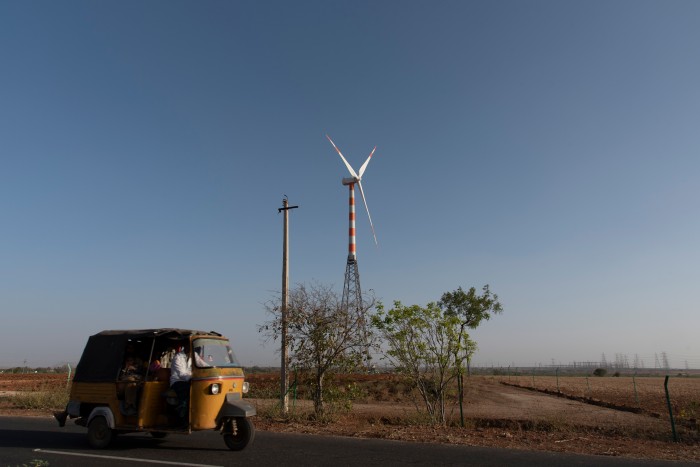 Photo of a wind turbine with a small vehicle in the foreground