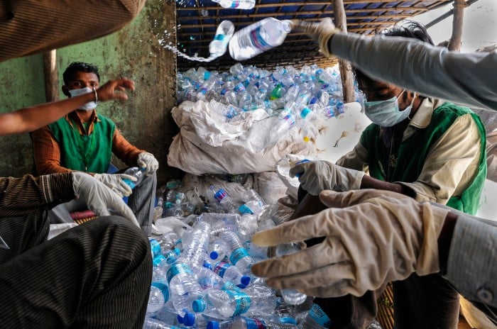 Image of men wearing gloves, handing out small bottles of water