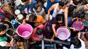 Image of people in India crowding to fill buckets with clean drinking water.