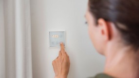 A woman using a smart thermostat in her home