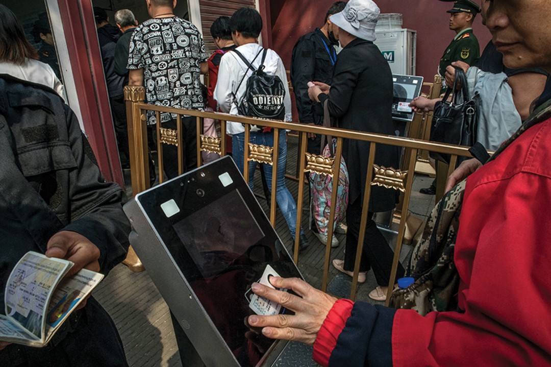 Photo of people tapping ID cards on a device before entering a building.