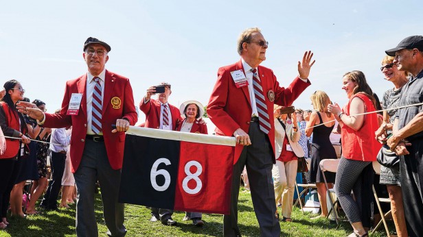 Photo of two men holding a banner reading "68", walking through a crowd