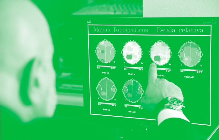 Photo of a man pointing at a computer screen showing brain activity maps.
