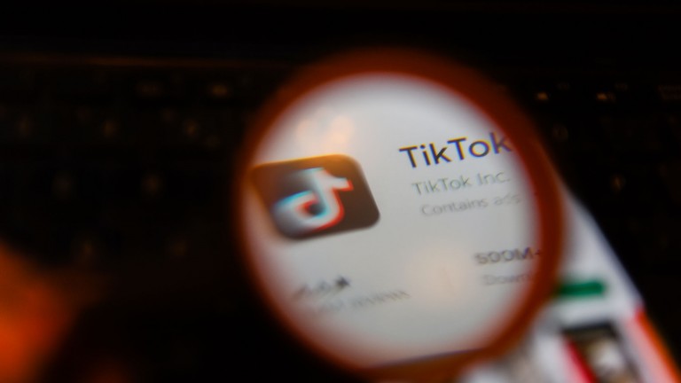 TikTok's app on a smartphone, with a magnifying glass in front