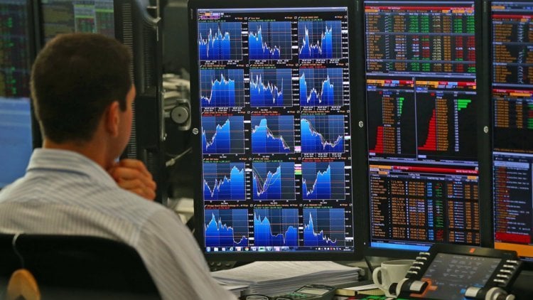 A trader sits in front of multiple screens