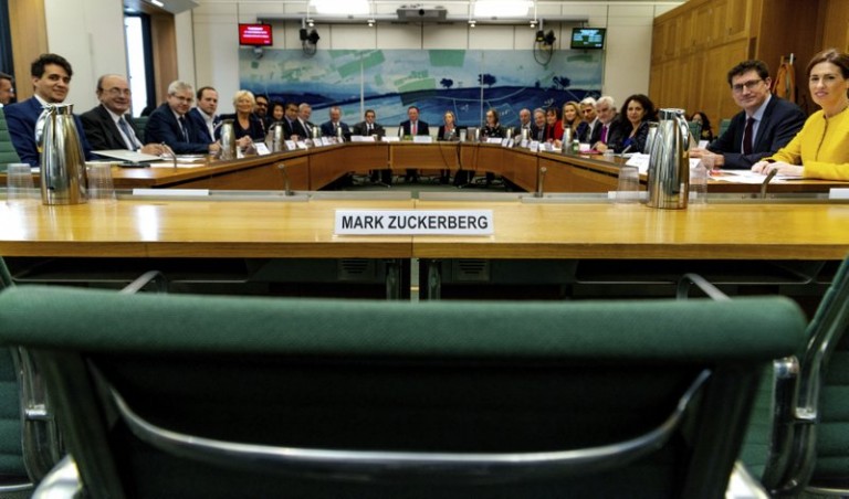 An empty chair with Mark Zuckerberg's name beside it, faced by lawmakers from multiple countries